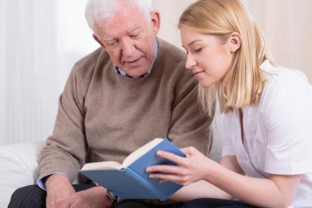 Photograph of an elderly gentleman looking at a book with a young woman