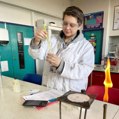 A-level student Paulina Patzova, wearing a white lab coat, carrying out an experiment in the science lab