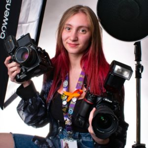 Photography student Rhiannon Cooper posing with two cameras in the college's photography studio