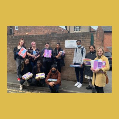 Picture of eight health and social care students and their tutor, holding duvet sets and standing by a sign that says 'The Have'