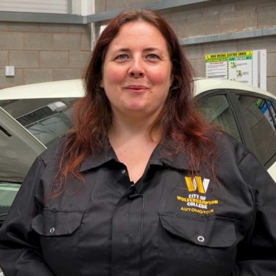 A picture of a female student (Tina Riley) standing behind a electric car