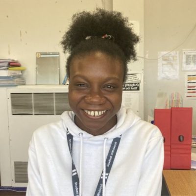 Business student Promise Anoke wearing a white hoodie and a grey college lanyard