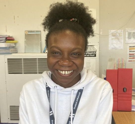 Business student Promise Anoke wearing a white hoodie and a grey college lanyard