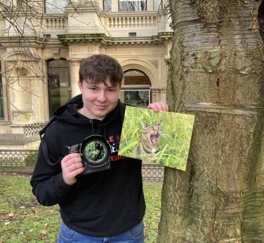 Photography student Devon Beckett pictures outside Wolverhampton Art Gallery, holding a camera and his award-winning picture of his pet cat