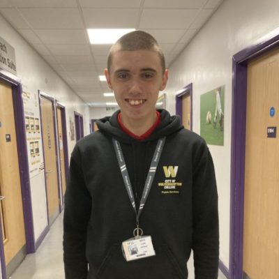 Public services student Louis Johnson wearing a black hoodie with the college logo in yellow and white on the lefthand side