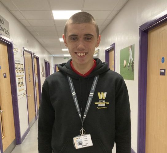 Public services student Louis Johnson wearing a black hoodie with the college logo in yellow and white on the lefthand side