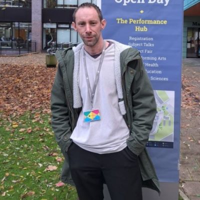 Access to HE student John Toye wearing a whit3ee t0shirt, grey jacket and a University of Wolverhampton lanyard