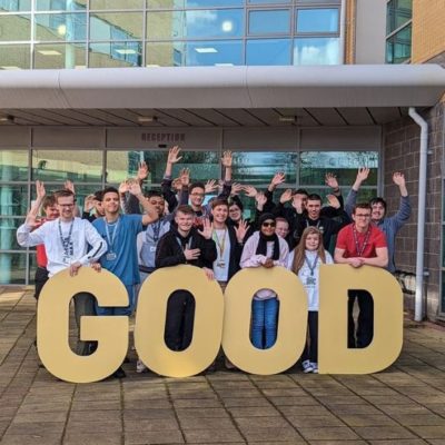 A group of students standing behind giant letters spelling the word 'Good'