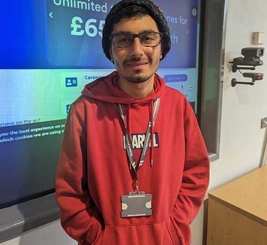 Bhuvanesh Mehton wearing a red top standing in front of a display board about the Midlands Metro