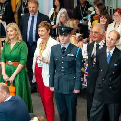 The Duchess of Edinburgh wearing a green dress, and the DUke of Edinburgh in a dark suit and blue tie with guests at the Coronation Big Lunch