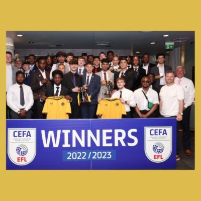 Group picture of members of the college football academy with their trophies, in front of a blue winners banner