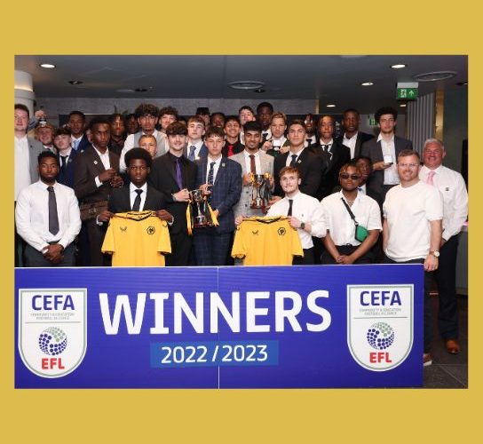 Group picture of members of the college football academy with their trophies, in front of a blue winners banner