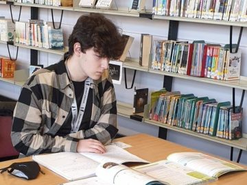 A Level student Luca Mardare wearing a black and cream checked shirt working in the college library