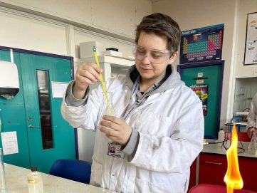 A-level student Paulina Patzova, wearing a white lab coat, carrying out an experiment in the science lab